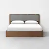A modern wooden bed frame with a gray upholstered headboard, dressed with white sheets, two neatly placed pillows, and positioned against a plain white wall on a gray floor.