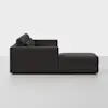 A modern dark gray sectional sofa with a chaise lounge, viewed from the side against a plain white background. The design is minimalistic with tufted back cushions and clean lines.