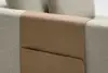 A close-up of a light gray fabric sofa with a tan leather organizer draped over the backrest, featuring a stitched pocket for holding items.