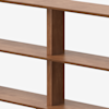 Close-up view of a wooden bookshelf with three horizontal shelves and a vertical divider, showing the grain and texture of the wood against a white background.