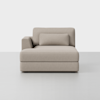 A modern, light beige upholstered chaise lounge with a left armrest and a matching rectangular cushion, set against a plain white background.
