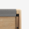 Close-up of the corner of a wooden object, possibly a piece of furniture, featuring a light wood finish, a grey felt or fabric covering on top, and black fasteners at the joints.