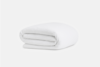 A neatly folded white blanket or comforter is placed on a plain white background. The fabric appears soft and textured, suggesting comfort and warmth.