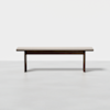 A simple wooden bench with a rectangular seat and four straight legs, placed on a light gray floor against a plain white background.