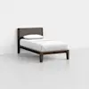 A single bed with a dark wooden frame, a padded fabric headboard, and white bedding with one pillow, placed in a minimalistic, empty room with light-colored walls and floor.