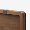 Close-up of a wooden board with rounded edges and a dark gray clip attached to the top edge, against a plain white background.