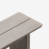 A close-up view of the corner of a light wood table with a modern design, featuring a narrow gap running lengthwise down the surface.