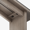 Close-up view of the underside corner of a wooden table, showing rounded edges, light wood grain, and two black circular elements attached to a recessed surface.