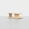 A modern, rectangular light wood coffee table with clean lines. It has a flat top, two vertical supports in the center, and a lower shelf, all set against a plain white background.