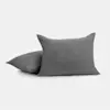 Two gray textured throw pillows, one propped upright and the other lying flat, set against a plain white background.
