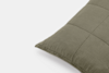 A close-up of the corner of an olive green quilted pillow against a white background. The pillow features visible stitching in a square pattern.