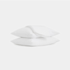 Two white pillows stacked on top of each other with a folded white blanket draped over the top pillow, all set against a plain white background.