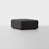 A square, dark gray upholstered ottoman with a minimalist design sits on a light, seamless floor against a plain white background.