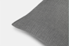 Close-up of a dark gray, textured pillow with a quilted pattern, set against a light background. Only a portion of the pillow is visible, showcasing the fabric’s details and stitching.