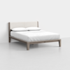 A modern bed with a light wood frame and an upholstered headboard, neatly made with white bedding and two pillows, placed in a minimal, bright room with a plain white wall and floor.