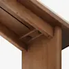 Close-up view of the underside of a wooden table showing the joint where the leg meets the tabletop, including exposed screws and clean, smooth wood grain.