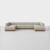 A large, modern beige sectional sofa with wooden base, arranged in a U-shape on a plain light gray floor against a white background.