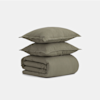 Two olive green pillows are stacked on top of a neatly folded matching duvet against a plain white background.