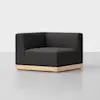 A modern, black upholstered corner chair with a low wooden base, set against a plain white background.