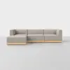 A modern, L-shaped sectional sofa with light gray upholstery and a wooden base, set against a plain white background.