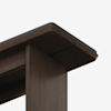 Close-up view of the corner of a dark wooden table or desk with a smooth finish and slightly rounded edges, photographed against a plain white background.