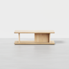 Minimalist wooden coffee table with a rectangular top, open sides, and a central vertical divider on a matching base, placed against a plain white background.