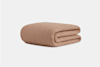 A neatly folded, light brown textured blanket displayed against a plain white background.