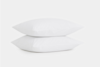 Two clean, white pillows are stacked on top of each other against a plain white background.