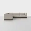 A modern, L-shaped sectional sofa with light beige upholstery and a dark wooden base, set against a plain, light gray background.