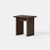 A small, modern wooden side table with a rectangular top and flat, solid legs, shown against a plain white background. The wood has a dark brown finish.