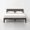 A modern bed with a dark wooden frame, fabric-upholstered headboard, white bedding, and two pillows, set against a plain white background.
