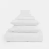 A neatly stacked set of white bedding, including pillows, folded sheets, and a comforter, arranged in a pyramid shape against a plain white background.