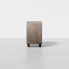 A minimalist, rectangular wooden cabinet stands on short cylindrical legs against a plain white background. The design is simple, with a smooth surface and no visible handles or decorations.