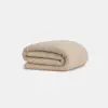 A beige, textured blanket neatly folded against a plain white background.