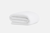 A neatly folded white blanket with a subtle textured pattern, placed on a plain white background.