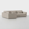 A modern, L-shaped beige sectional sofa with clean lines and plush cushions sits on a seamless light gray floor against a plain white background.