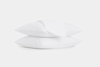 Two white pillows stacked on top of each other with a folded white sheet draped over the top pillow, all against a plain white background.