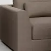 Close-up view of the arm and seat of a modern, brown upholstered sofa with a matching rectangular cushion. The fabric has a subtle textured pattern, and the design features clean, straight lines.