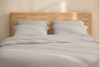 A neatly folded stack of white bed linens, including sheets and pillowcases, set against a plain white background.