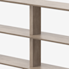 Close-up view of a wooden shelf with vertical and horizontal panels intersecting, creating rectangular compartments. The wood has a light brown finish and a smooth texture. The background is plain and white.
