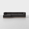 A modern dark gray sectional sofa with low backrests and armrests, set on a light wood base, placed in a minimalistic room with a light gray floor and plain white wall.
