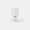 A small cylindrical table lamp with a cream-colored base and a simple cylindrical fabric shade.