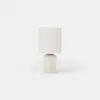 A small cylindrical table lamp with a cream-colored base and a simple cylindrical fabric shade.