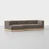 A modern, sectional sofa with brown upholstery and a light wooden base, positioned on a light grey floor against a plain white background.