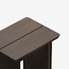 A close-up view of the top corner of a dark brown wooden table with a distinctive groove running lengthwise down the middle. The background is plain white.