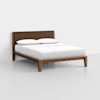 A modern wooden bed frame with a brown upholstered headboard, neatly made with white bedding and two white pillows, set against a plain white wall and floor.