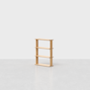 A small, light wood bookshelf with four shelves is placed on a gray, textured floor against a plain white background. The design is simple and modern, with clean, straight lines.