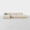 A modern, light beige sectional sofa with a low wooden base is set against a plain white background and floor. The sofa has clean lines and a minimalist design.