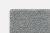 Close-up view of the top left corner of a rectangular, light gray carpet with a soft, textured surface, set against a plain white background.