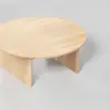 Round wooden coffee table with a smooth, light-colored surface and three wide, flat legs, shown on a light gray background.